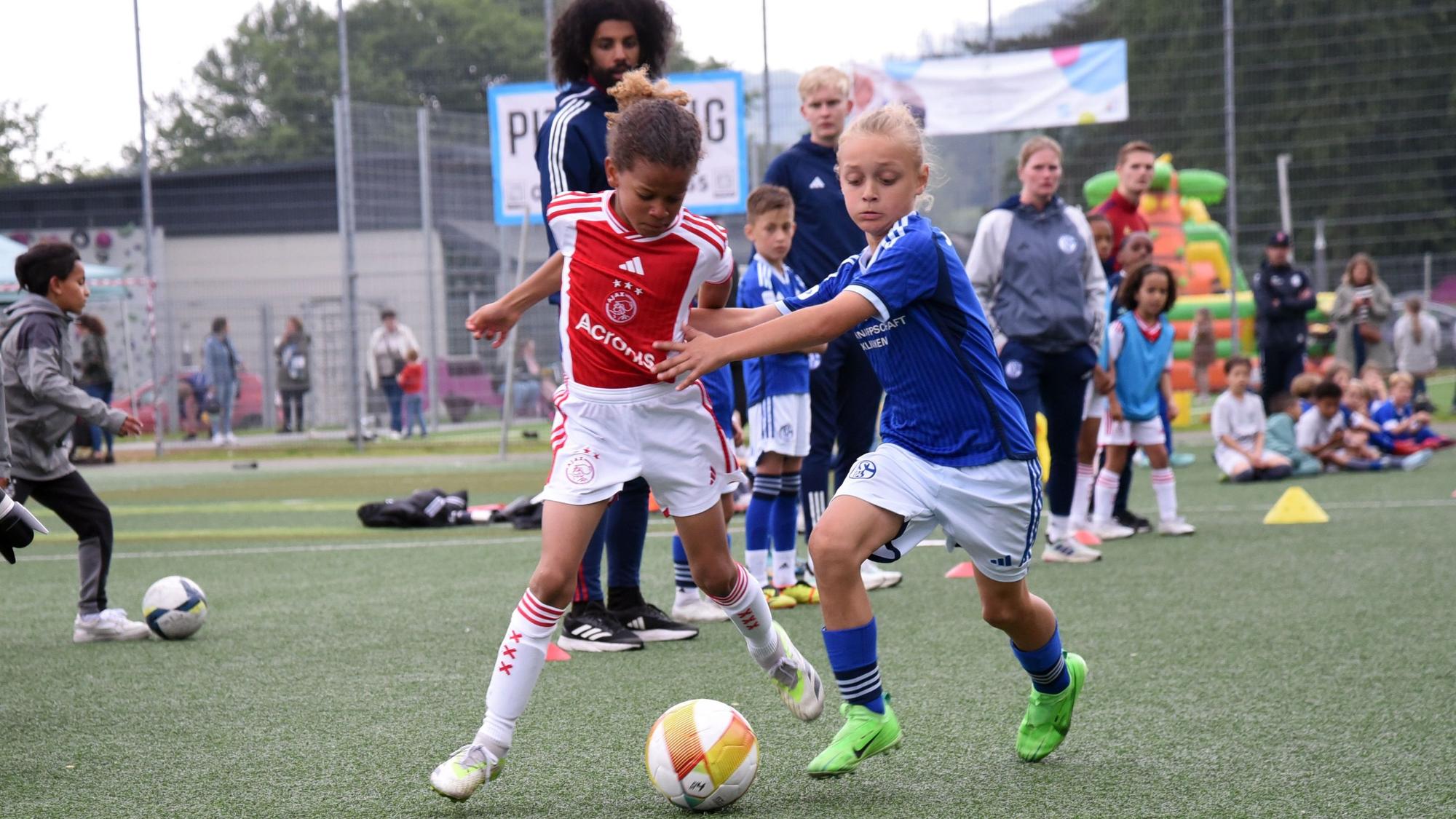 Fußballer von Ajax Amsterdam und dem FC Schalke 04 im Zweikampf.