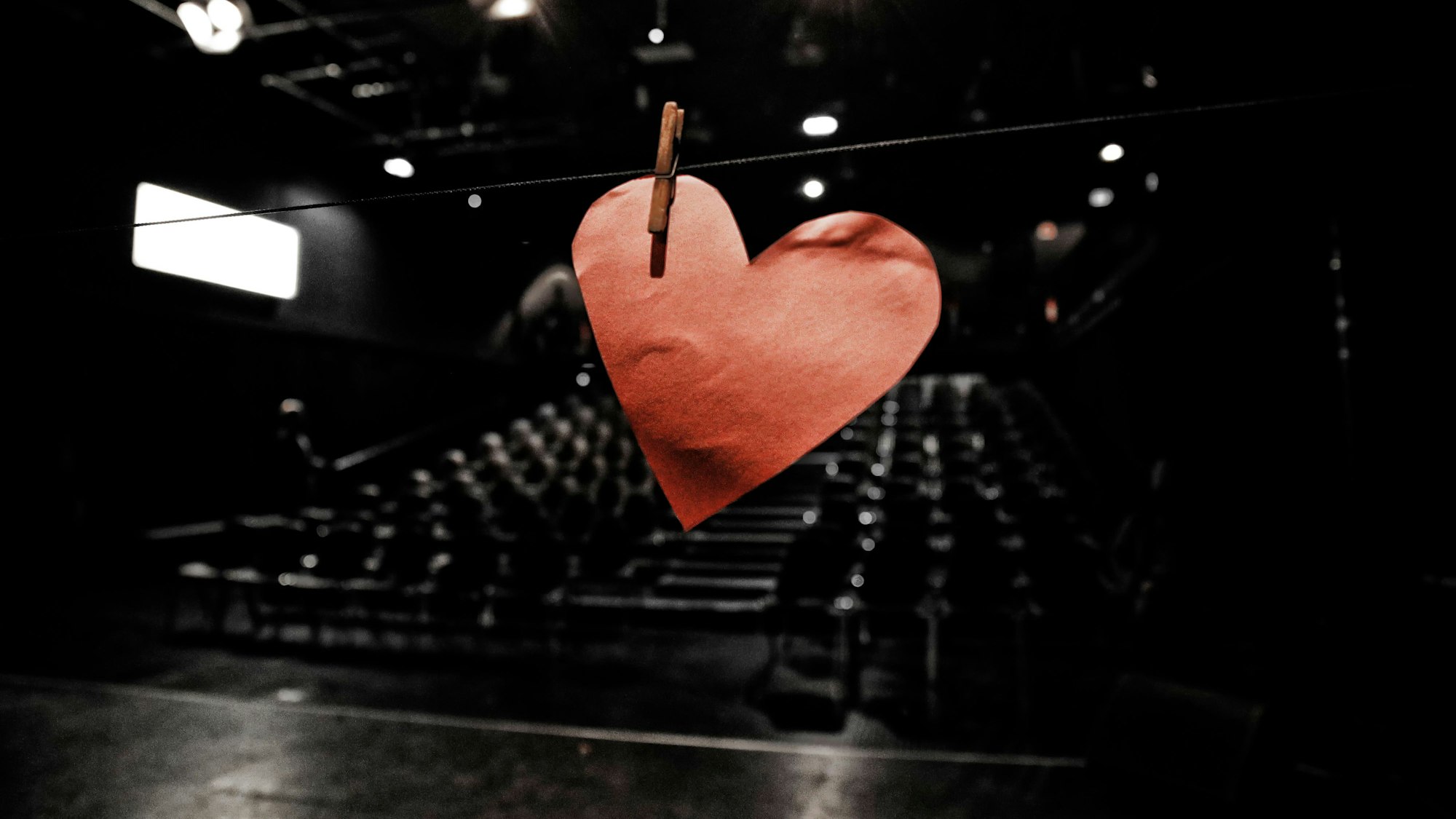 Ein rotes Pappherz ist im Saal der Studiobühne Köln mit einer Wäscheklammer an einer Leine befestigt.