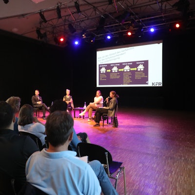 Menschen sitzen in der Alten Feuerwache und folgen der Informationsveranstaltung „Wie funktioniert eine Erstaufnahmeeinrichtung?“.