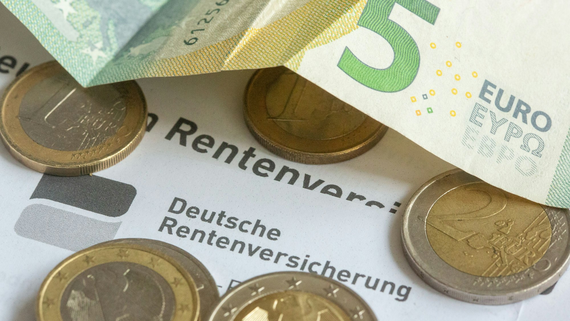 Münzen und eine Banknote liegen auf einer Renteninformation der Deutschen Rentenversicherung.