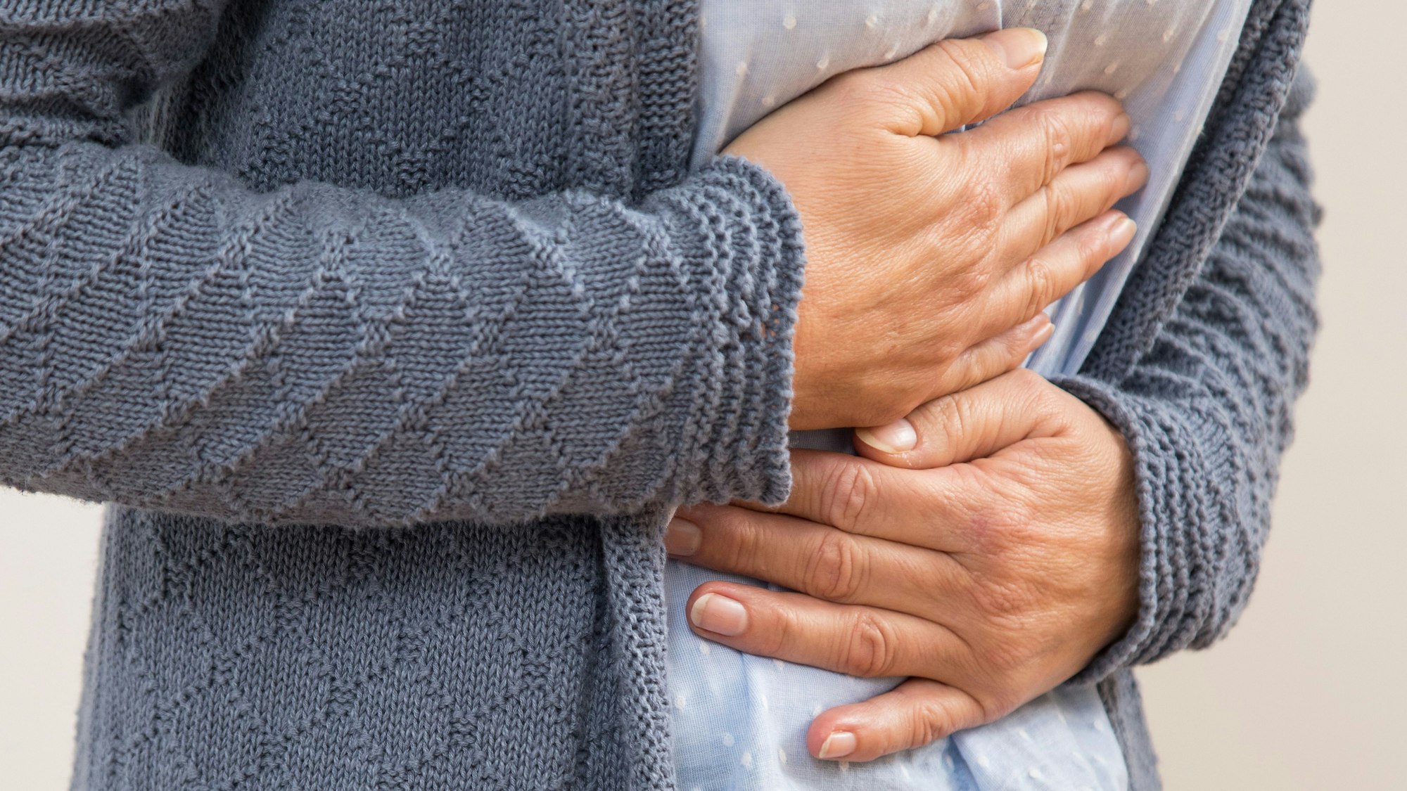 Person hält sich mit beiden Händen den Magen.