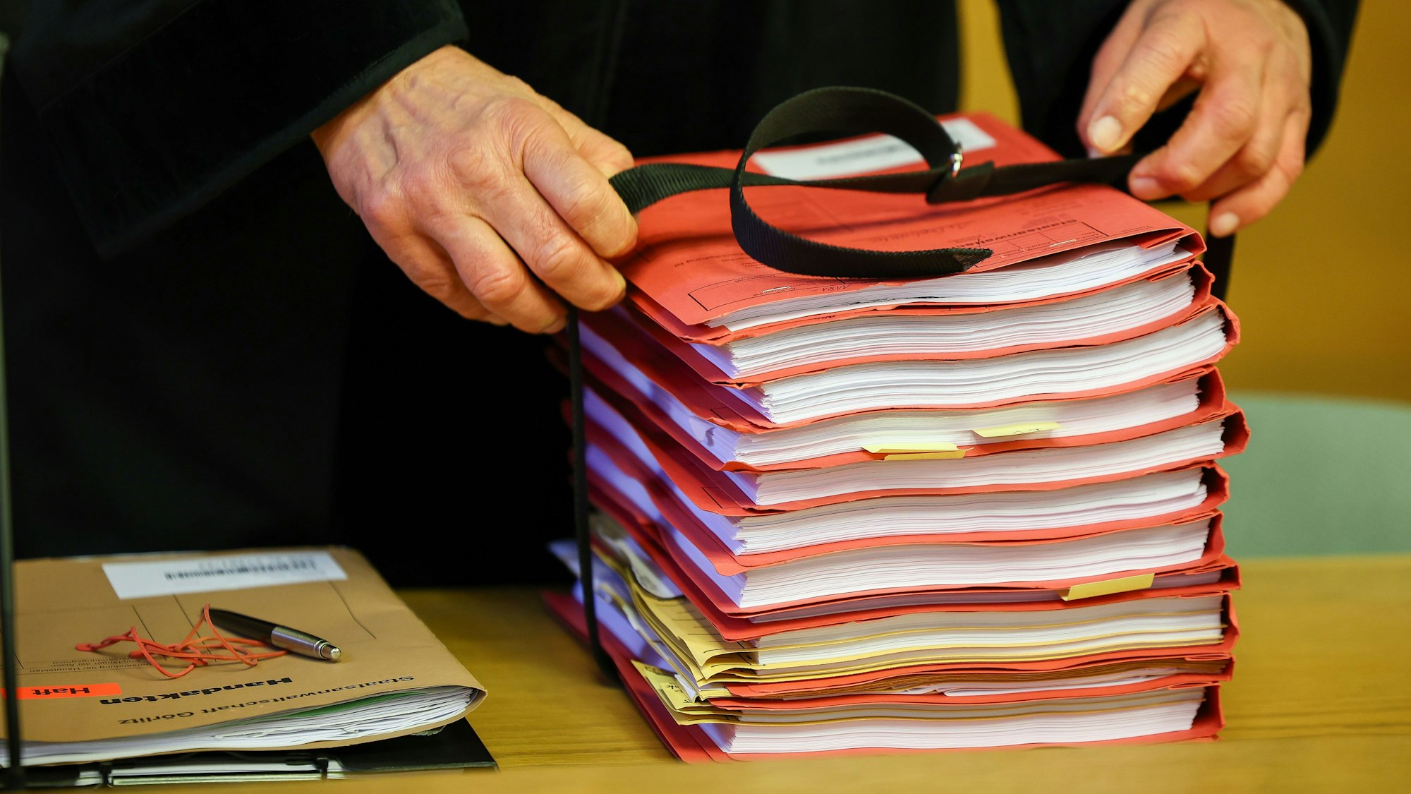 Der Staatsanwalt legt einen Stapel Akten vor Prozessbeginn auf seinen Tisch im Landgericht.