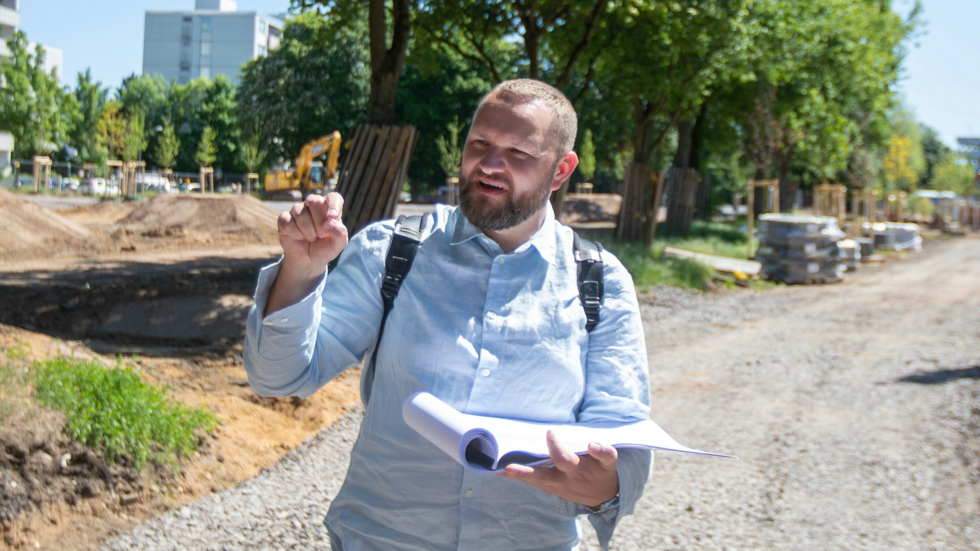 Ein Landschaftsarchitekt erklärt bei einem Rundgang über eine Baustelle die Pläne für einen neuen Park.