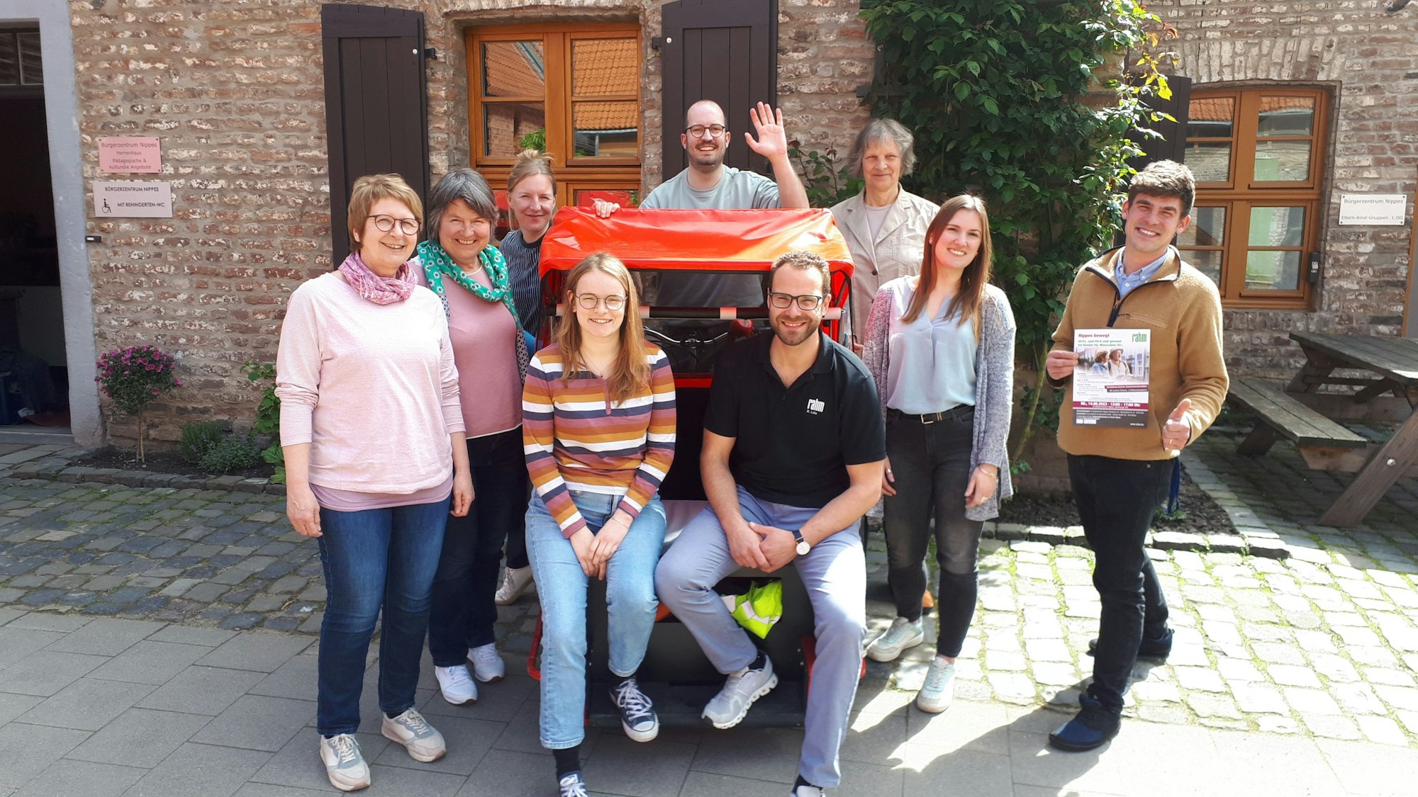 Eine Gruppe Menscehn hat sich um eine Fahrrad-Rikscha herum aufgestellt.