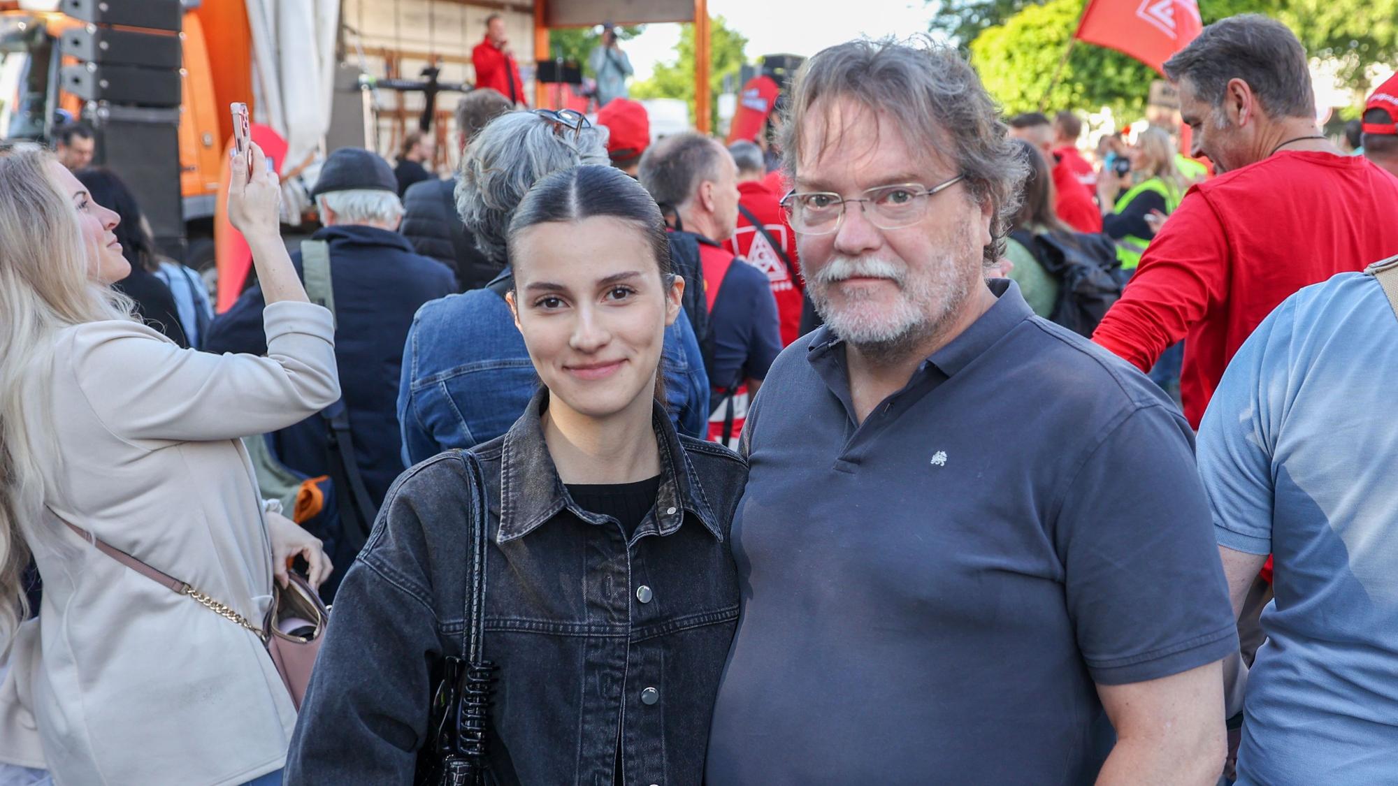 Eine junge Frau mit dunkler Jeansjacke steht neben ihrem Vater.