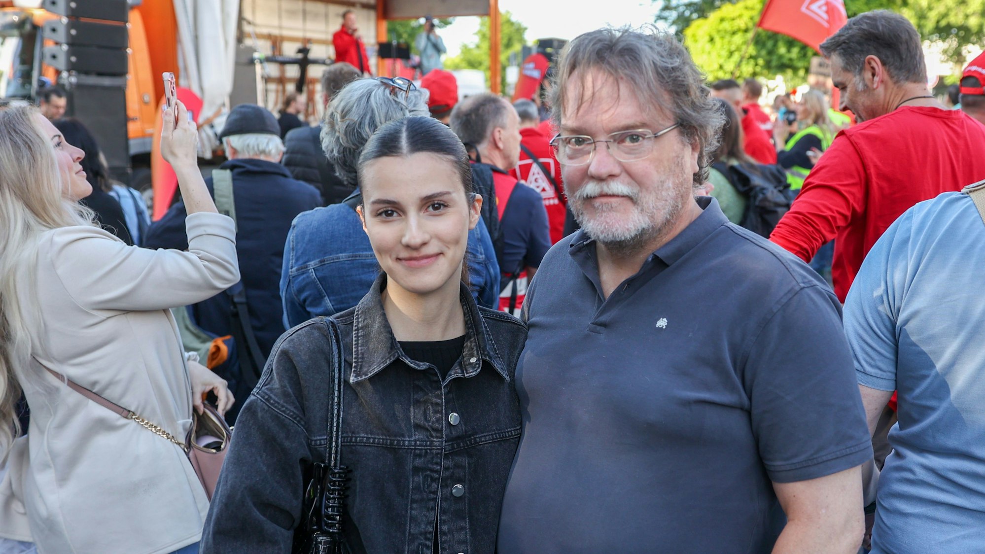 Eine junge Frau mit dunkler Jeansjacke steht neben ihrem Vater.