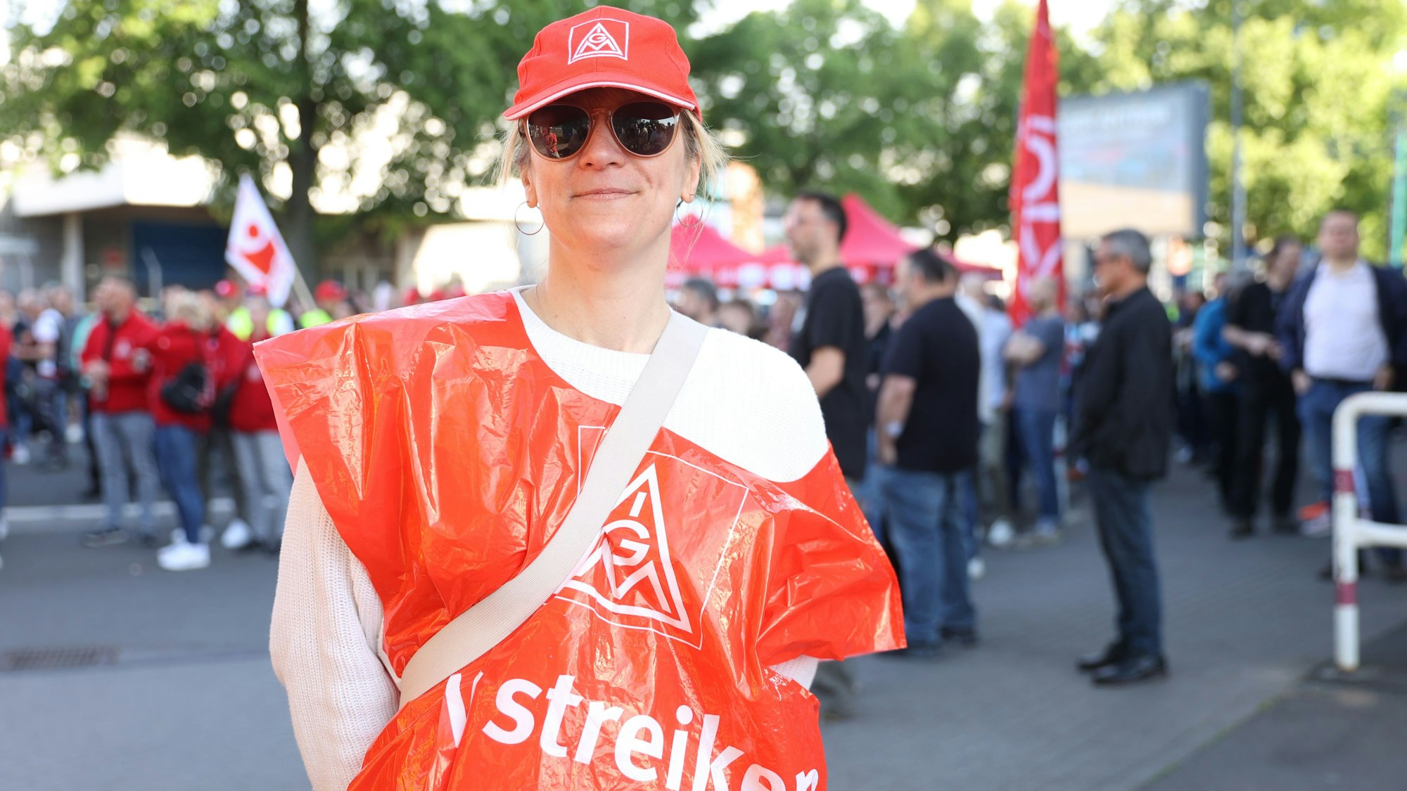 Nina Herbert, 45 Jahre alt, steht in roter Streik-Uniform der IG Metall und lächelt in die Kamera.