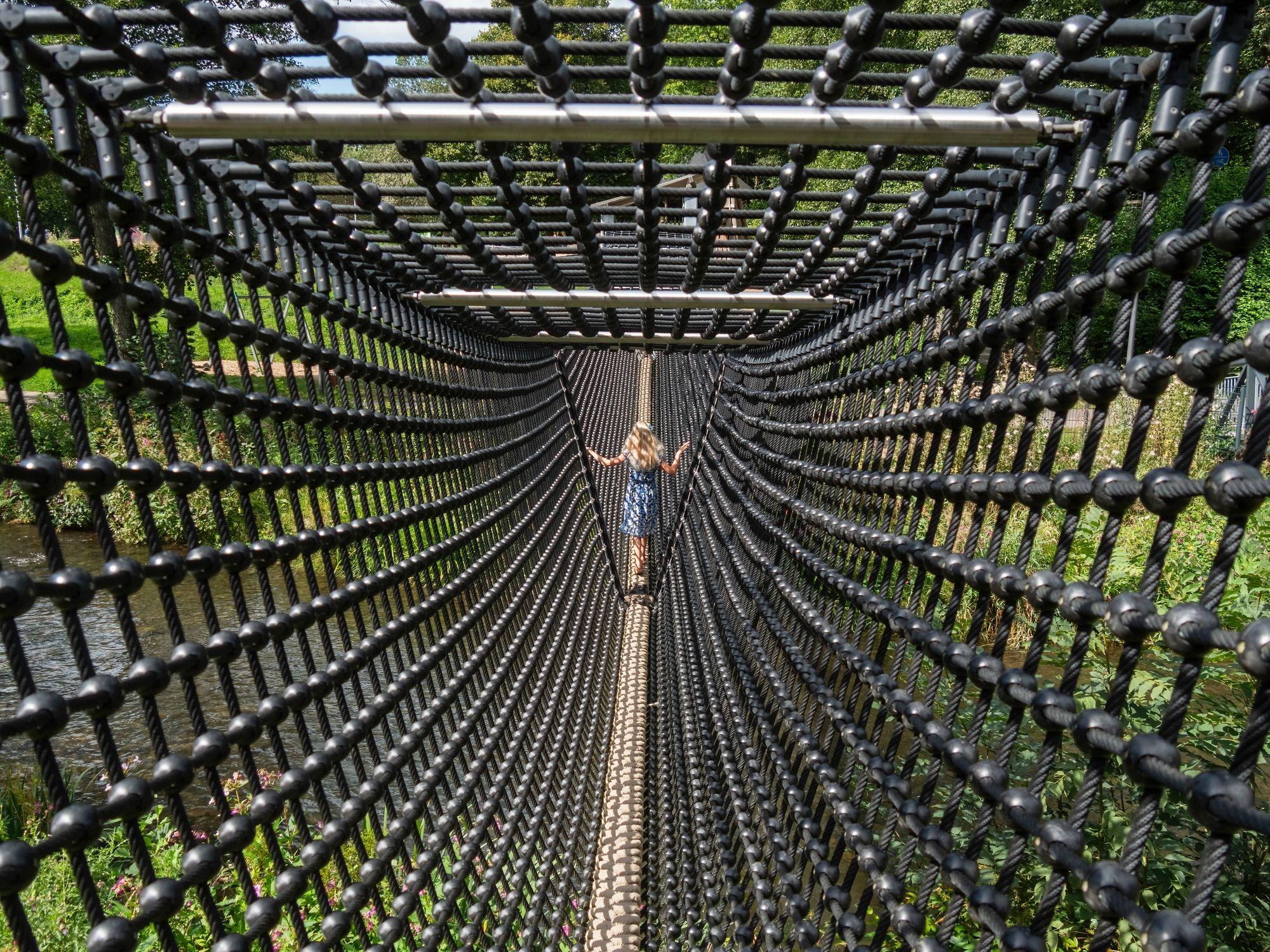 Ein Mädchen läuft in einer geschlossenen Hängebrücke.