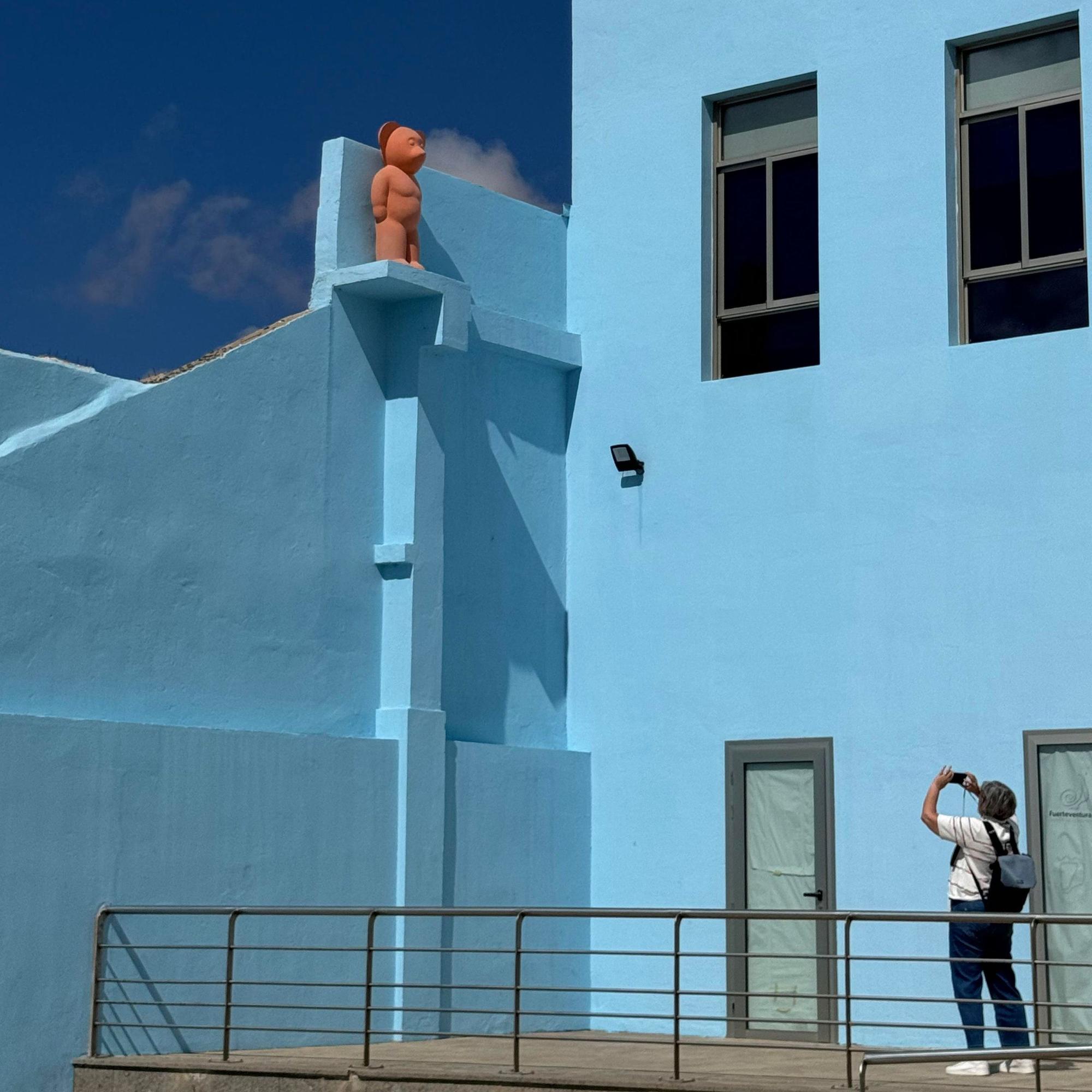 Eine Frau fotografiert ein hellblau gestrichenes Haus.