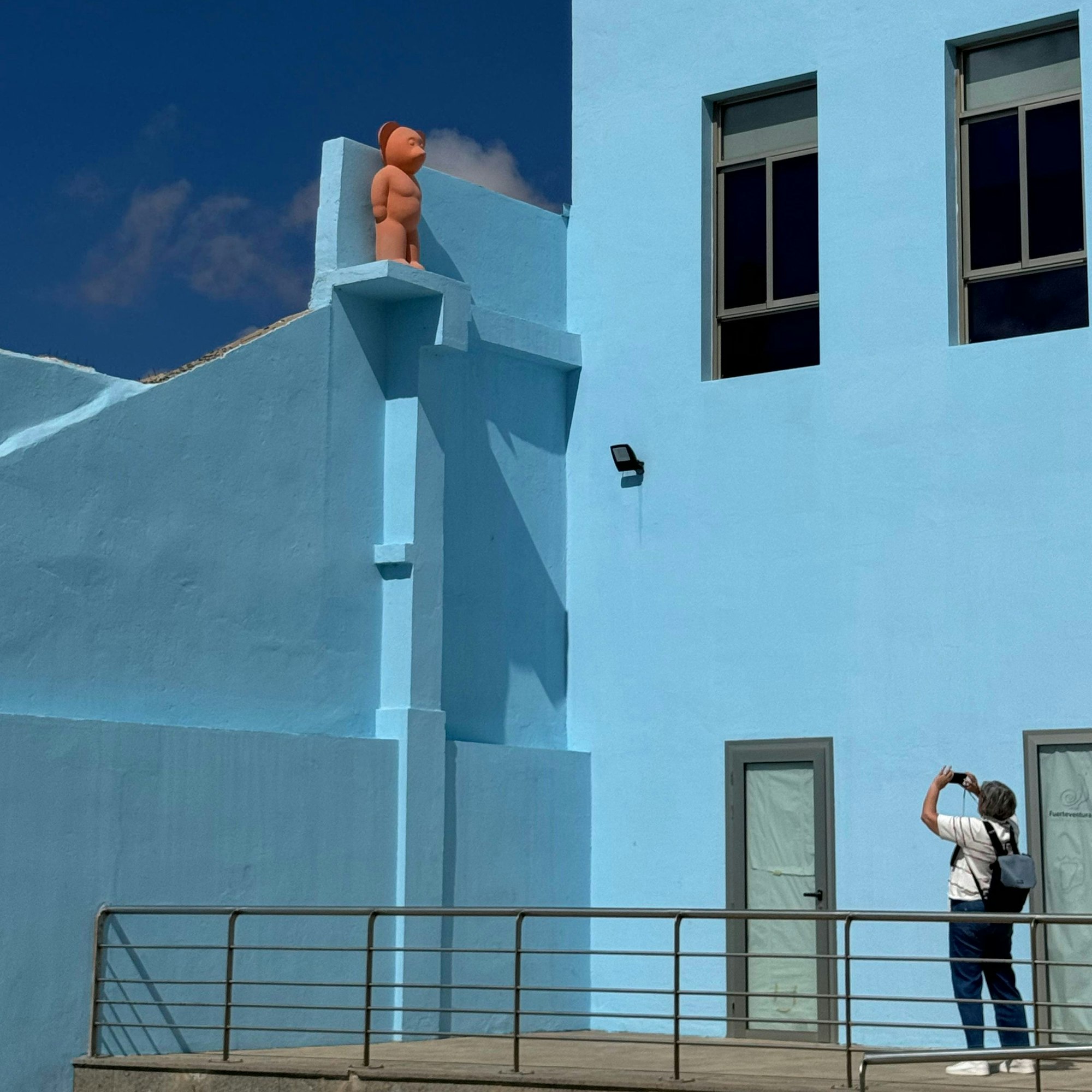 Eine Frau fotografiert ein hellblau gestrichenes Haus.
