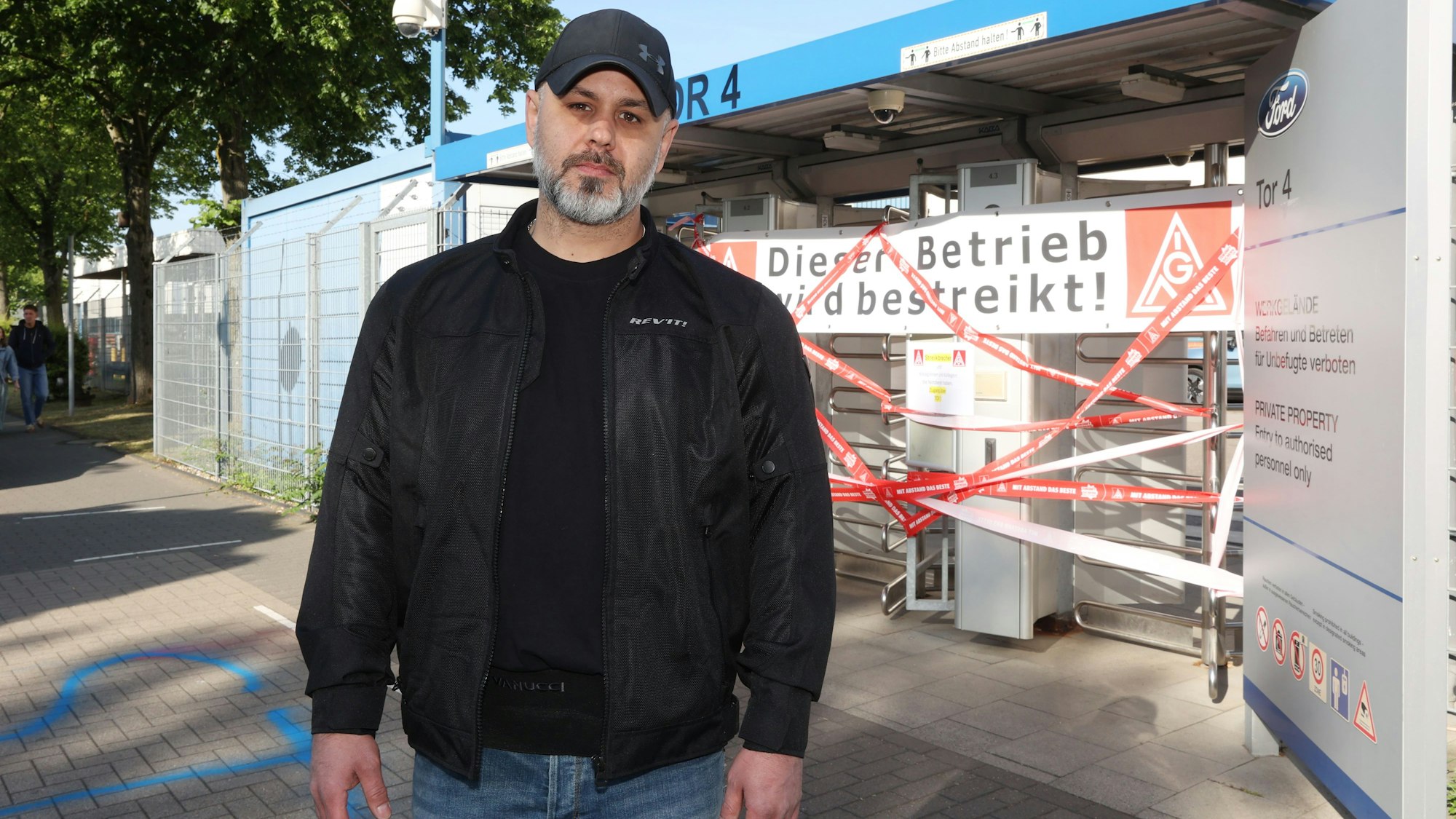 Joachim Reitmeier steht vor einem verriegelten Tor mit der Aufschrift: Dieser Betrieb wird bestreikt.