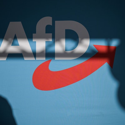 Ein Redner wirft einen Schatten auf die Bühnenrückwand mit AfD-Schriftzug auf einer Veranstaltung.