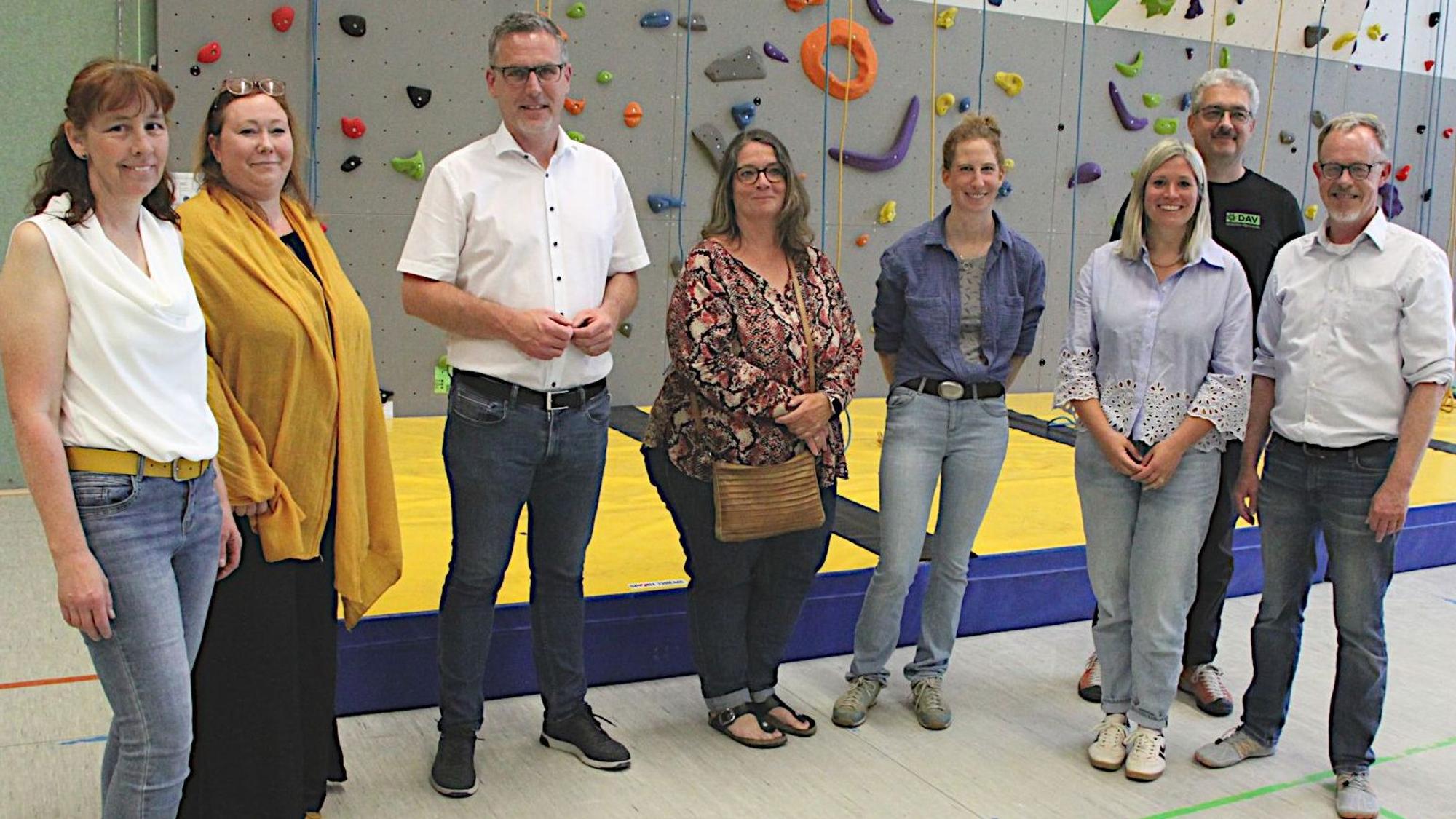 Die Beteiligten haben sich zum Foto vor die Kletterwand gestellt.