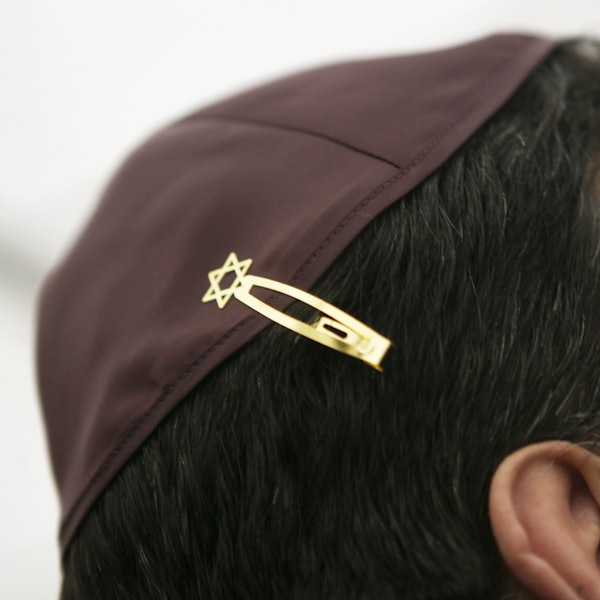 Ein Jude hat sich bei den Feierlichkeiten einer Grundsteinlegung für eine Synagoge seine Kopfbedeckung (Kippa) mit einer Davidstern-Klammer am Haar befestigt.