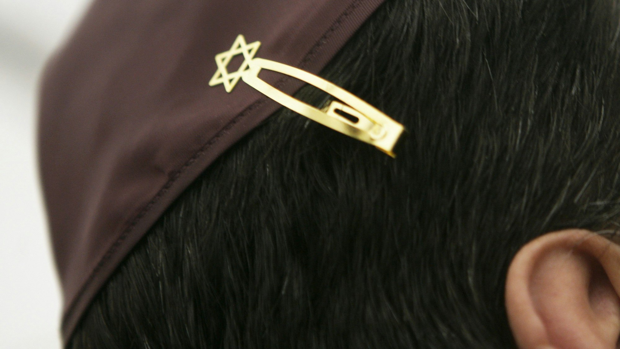 Ein Jude hat sich bei den Feierlichkeiten einer Grundsteinlegung für eine Synagoge seine Kopfbedeckung (Kippa) mit einer Davidstern-Klammer am Haar befestigt.