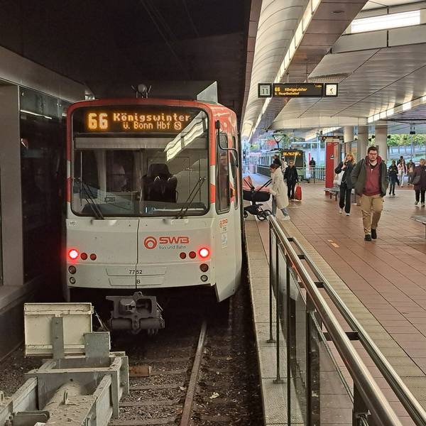 Die Stadtbahnlinie 66 hält am Siegburger Bahnhof. Am Gleis laufen Menschen oder steigen ein und aus.