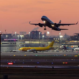 Flugverkehr vor der Skyline von Köln und den Terminals bei Sonnenuntergang und klarem Himmel am Flughafen Köln/Bonn