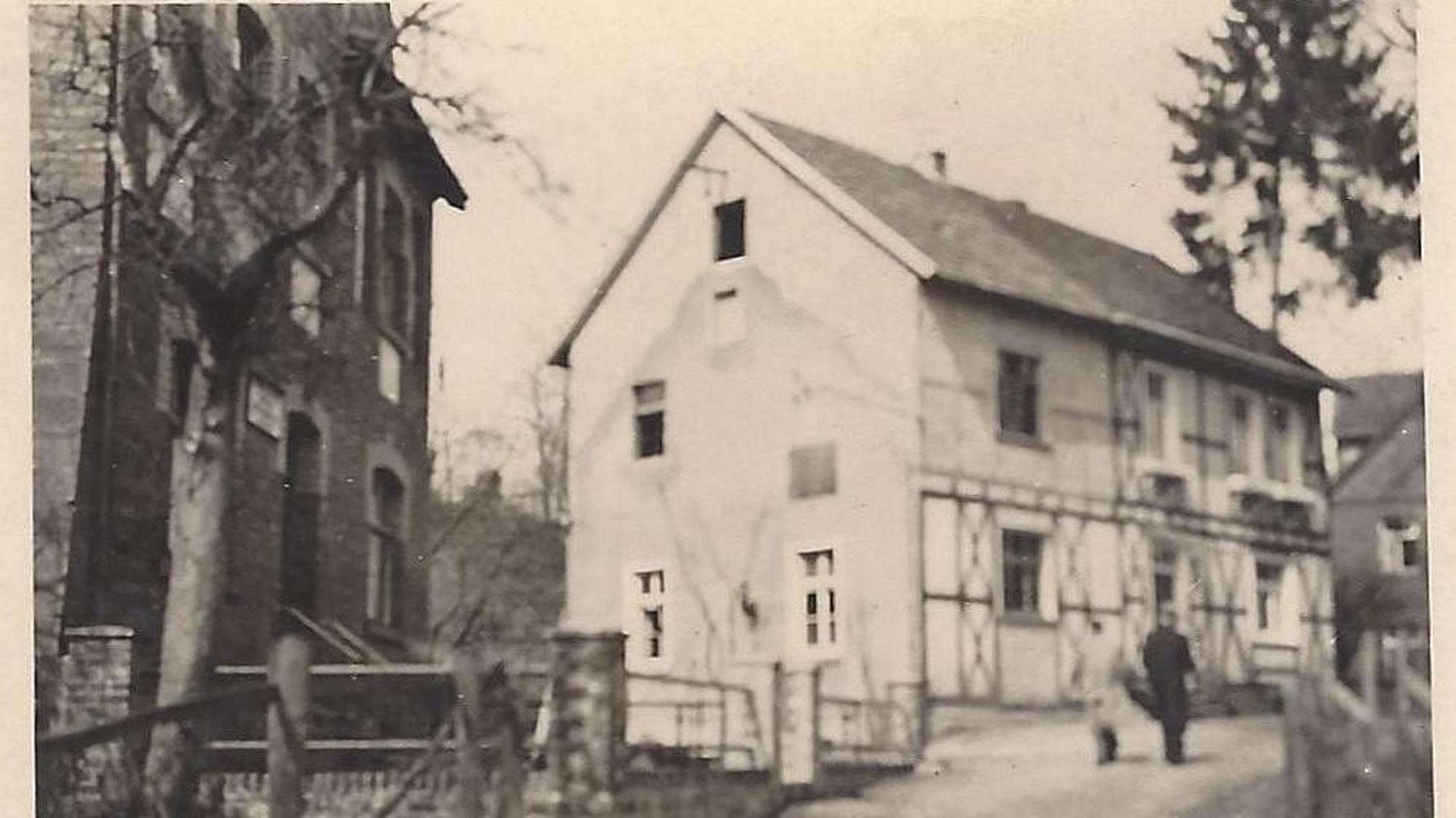 Historische Ansicht einer Dorfstraße auf einem Schwarz-Weiß-Foto.