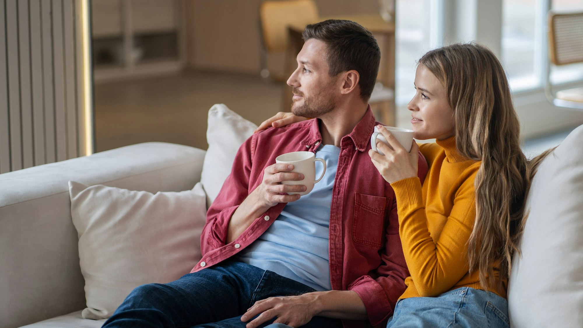 Eine Frau und ein Mann sitzen auf einem Sofa und denken nach.