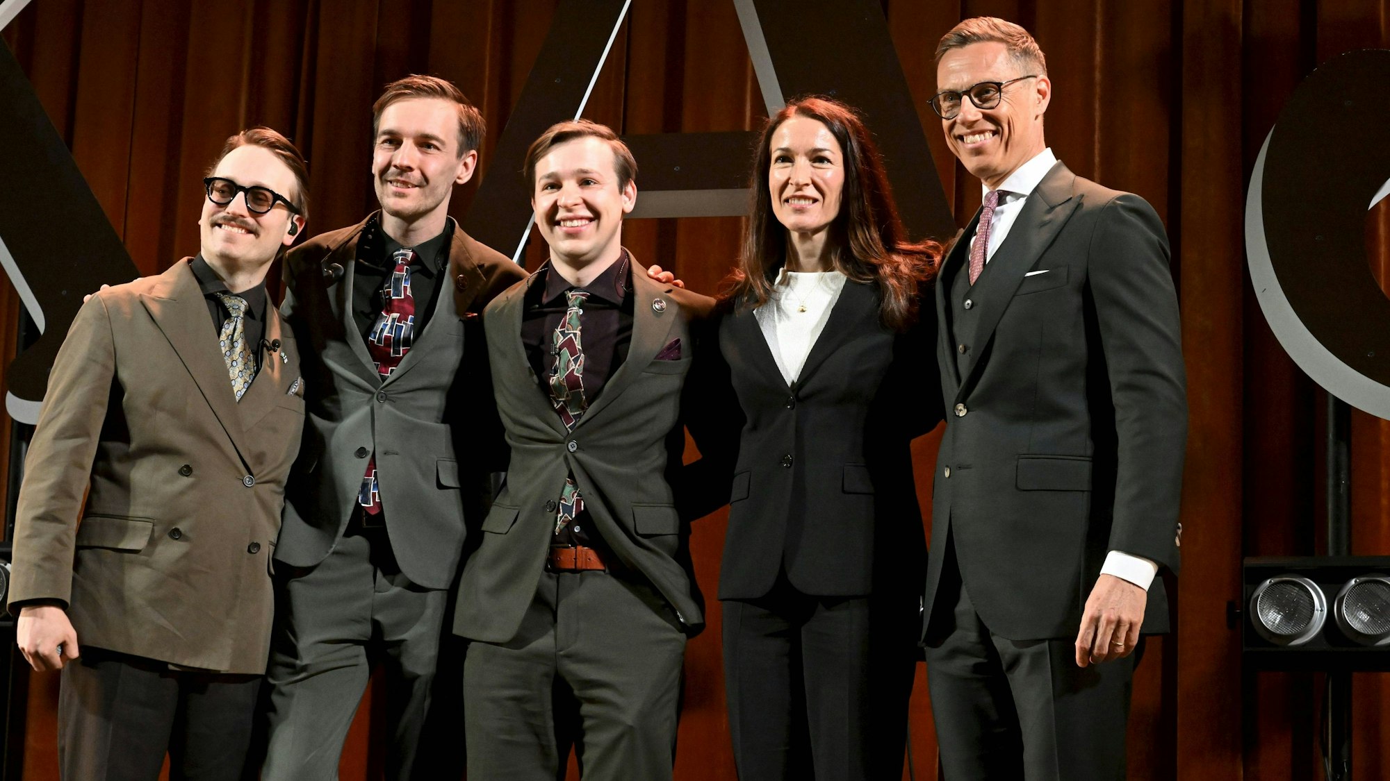 Präsident Alexander Stubb und seine Frau Suzanne Innes-Stubb posieren auf der Bühne zusammen mit Axel Åhman (links), Kevin Holmström und Jakob Norrgard von der Humorgruppe KAJ.
