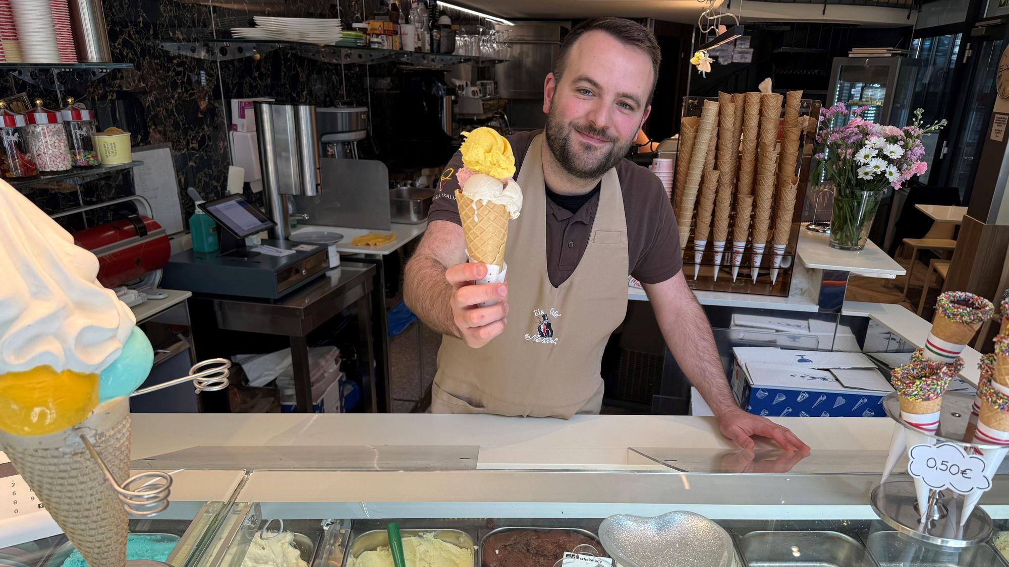 Alessandro Martini übergibt ein Hörnchen mit Eis an seiner Eisdiele