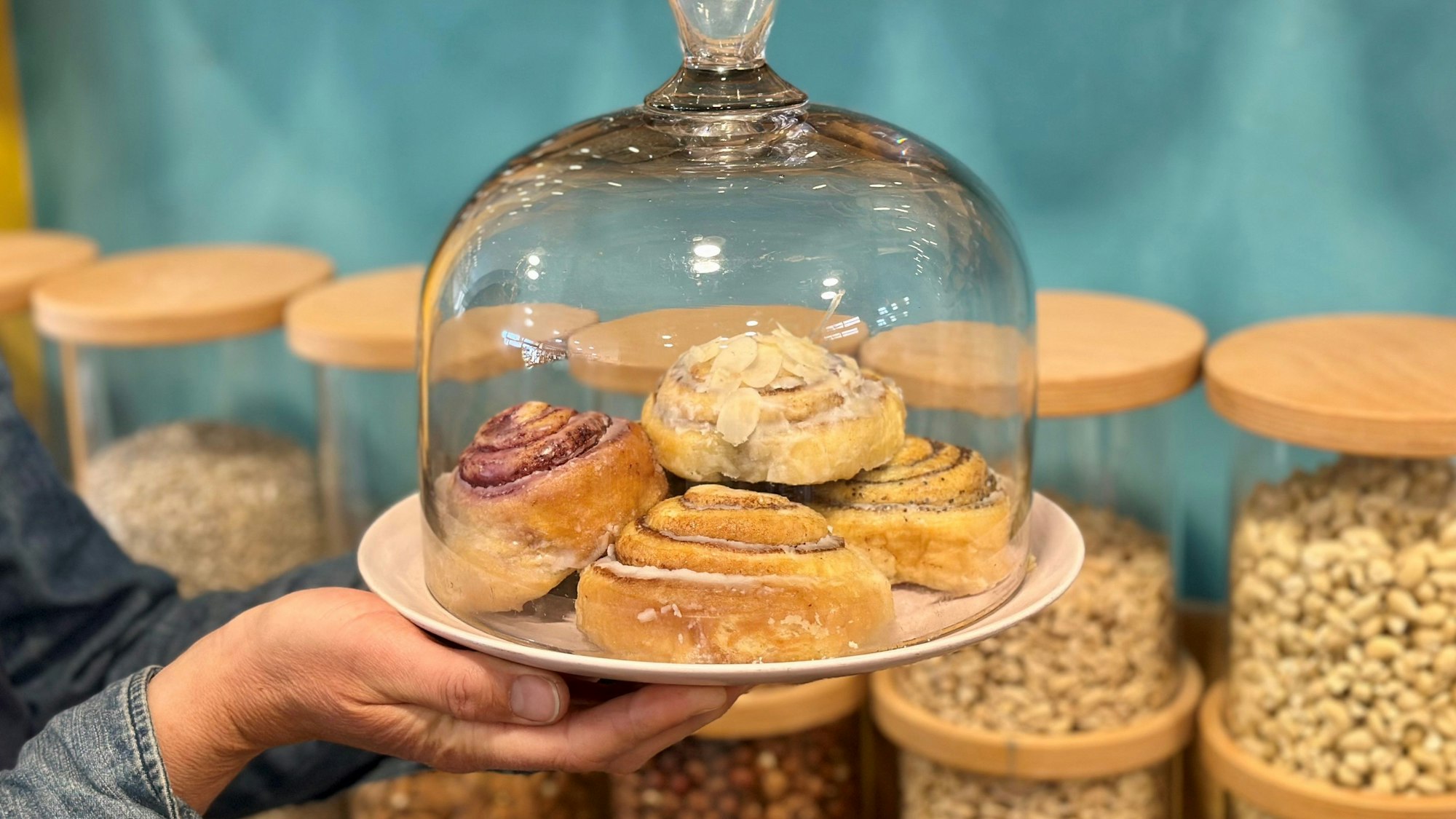 Zu sehen ist ein Teller Zimtschnecken unter einer Glasglocke.