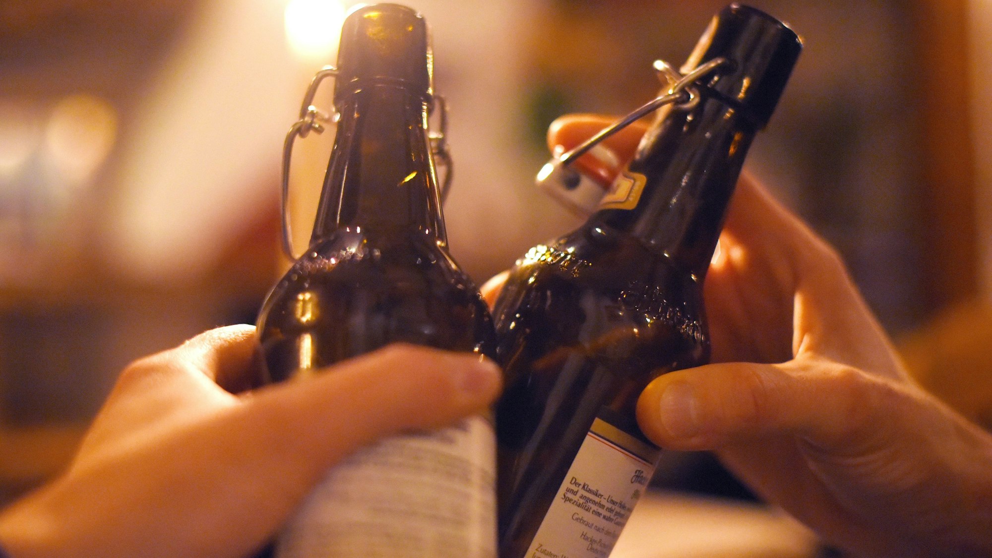 Zwei Händen mit Bierflaschen beim Anstoßen.