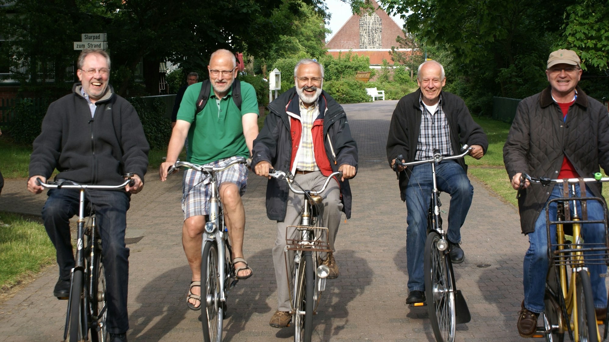 Fünf Männer fahren nebeneinander gut gelaunt Fahrrad.
