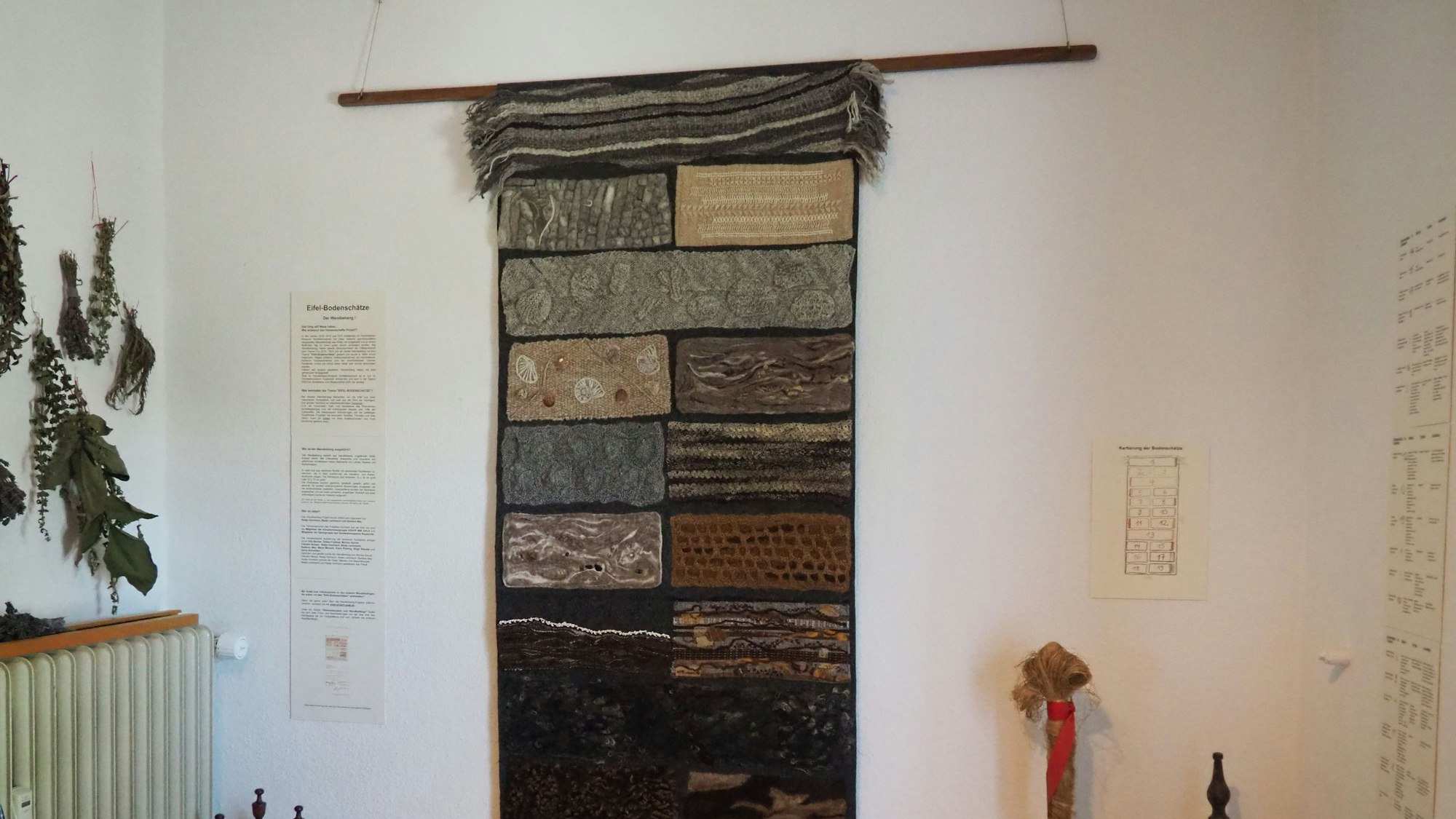 Ein Wandteppich hängt an einer weißen Wand.