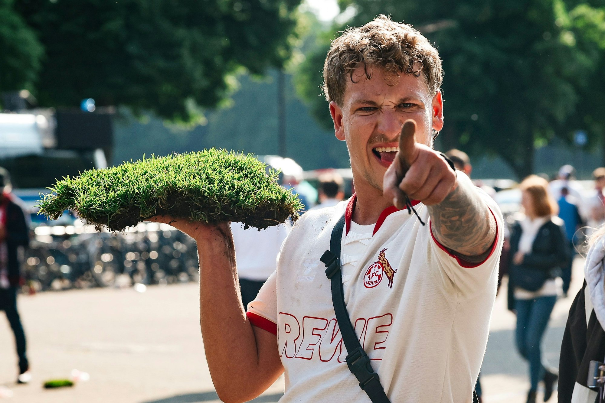 Köln-Fan mit Stück Rasen in der Hand