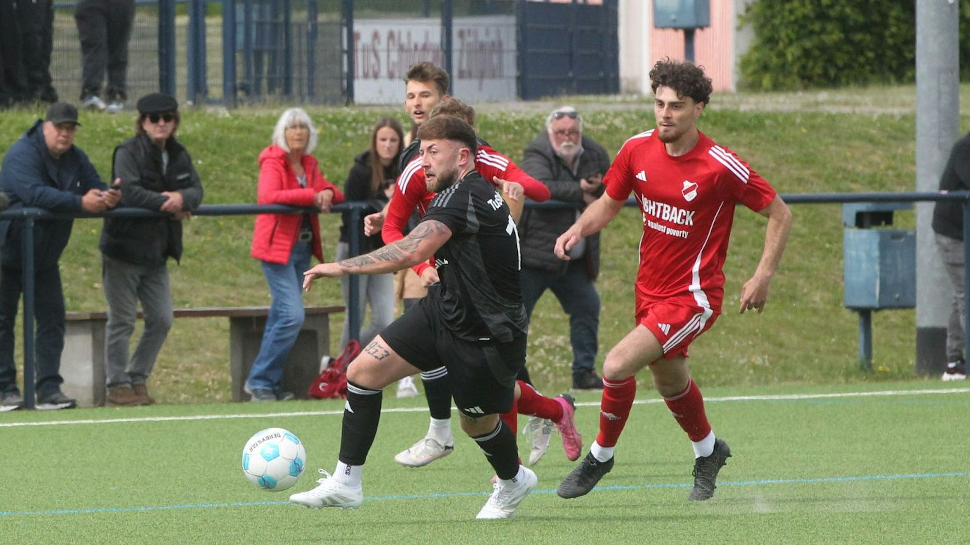 Das Bild zeigt einen Fußballer, den zwei Gegenspieler nicht aufhalten können.