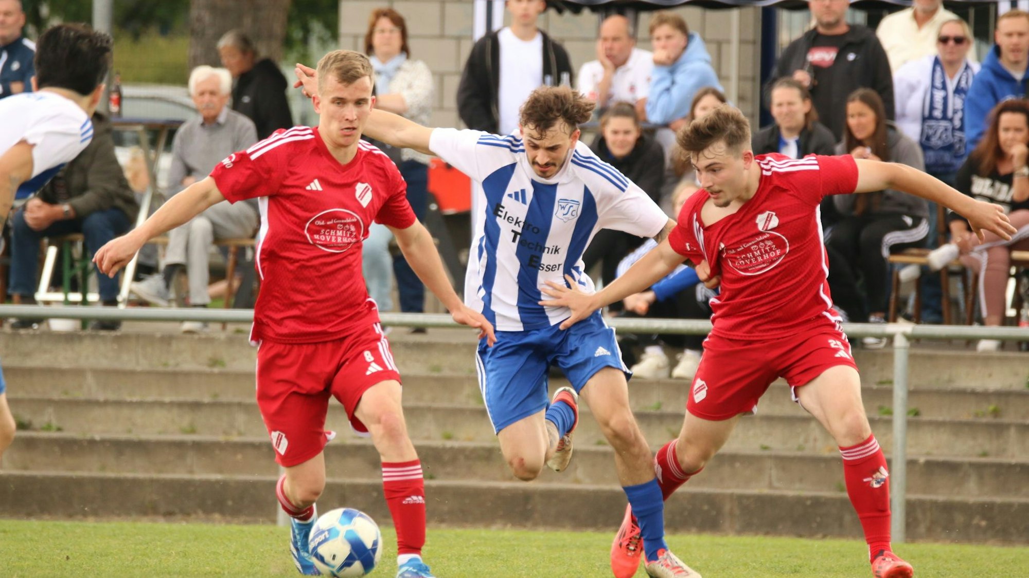 Das Bild zeigt einen Fußballer, dem zwei Gegner den Ball abnehmen wollen.