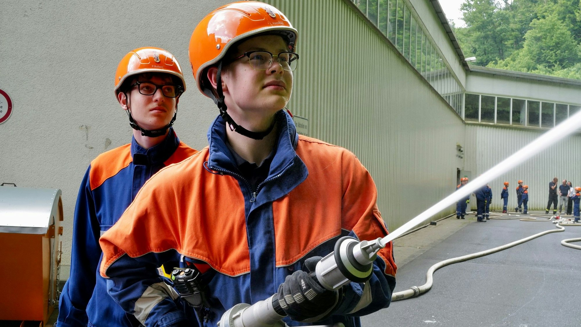 Zwei Jungfeuerwehrleute arbeiten bei der Übung mit einem Wasserschlauch.