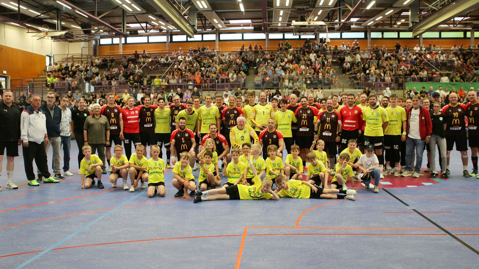 Gruppenbild beider Mannschaften und der Schiedsrichter vor der Tribüne in der Eugen-Haas-Halle.