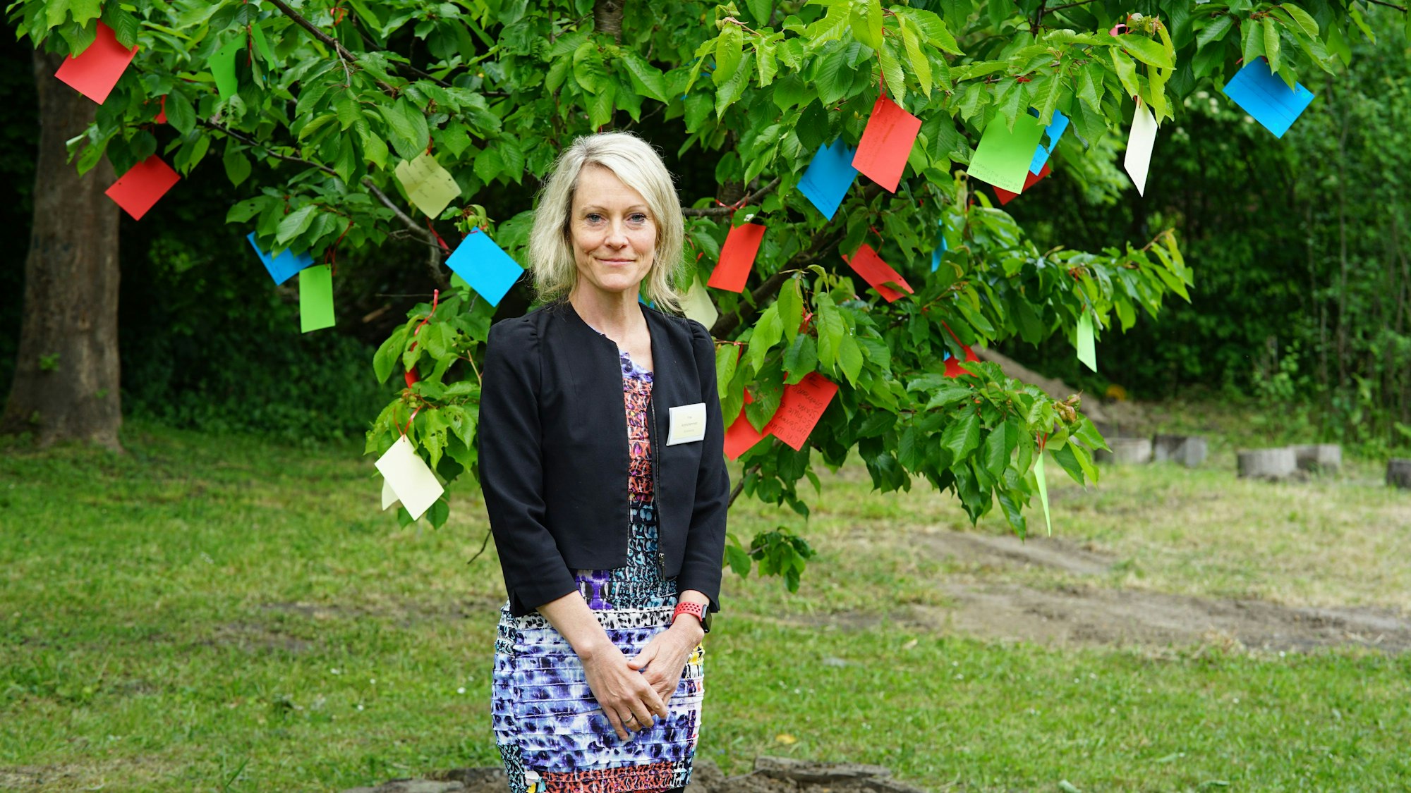 Auf dem Bild ist die Schulleiterin vor dem Wünschebaum zu sehen.