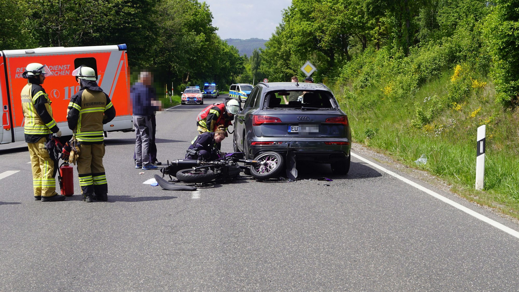 Das Bild zeigt das Motorrad nach dem Unfall. Es liegt hinter einem Audi auf der Straße.