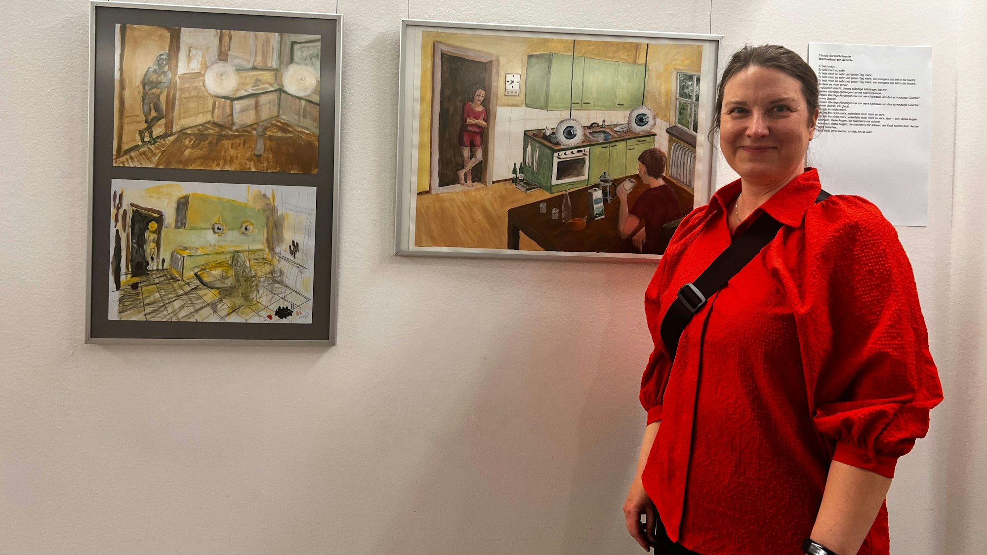 Eine Frau steht vor Bildern an einer Wand.