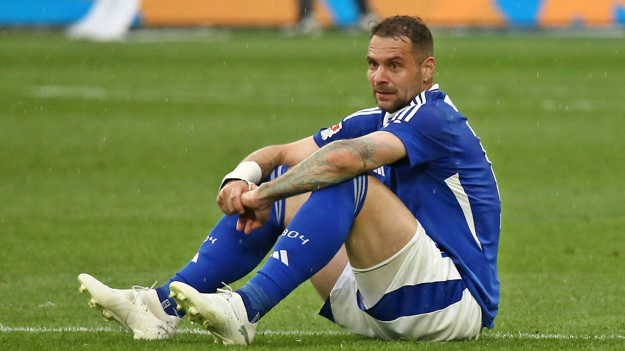 Pierre-Michel Lasogga sitzt mit enttäuschtem Gesicht auf dem Rasen.