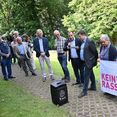 Beteiligte der Veranstaltung halten ein Anti-Rassismus-Plakat in der Hand.