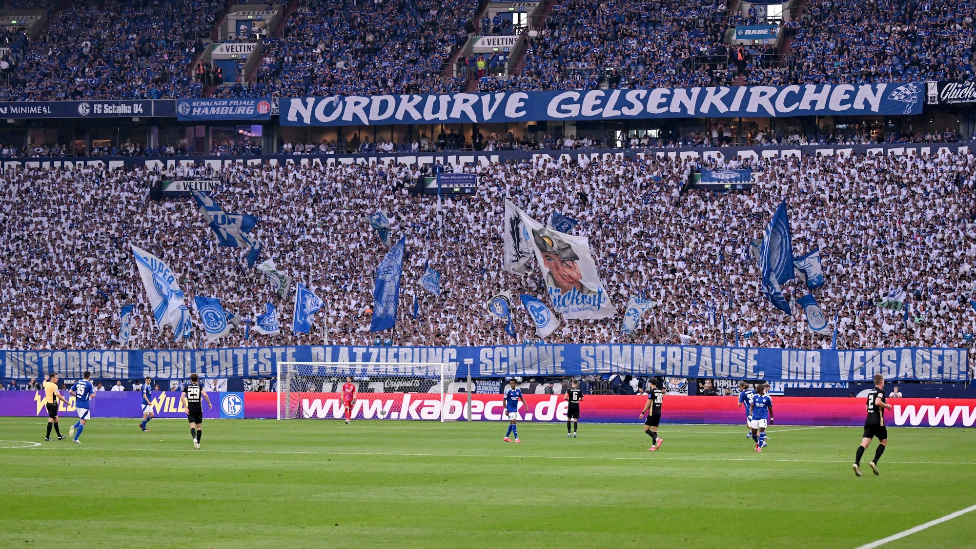 Die Schalker Fans haben ein Plakat in der Länge des Spielfelds mit der Aufschrift "Historisch schlechteste Platzierung - Schöne Sommerpause, ihr Versager!" angehangen.