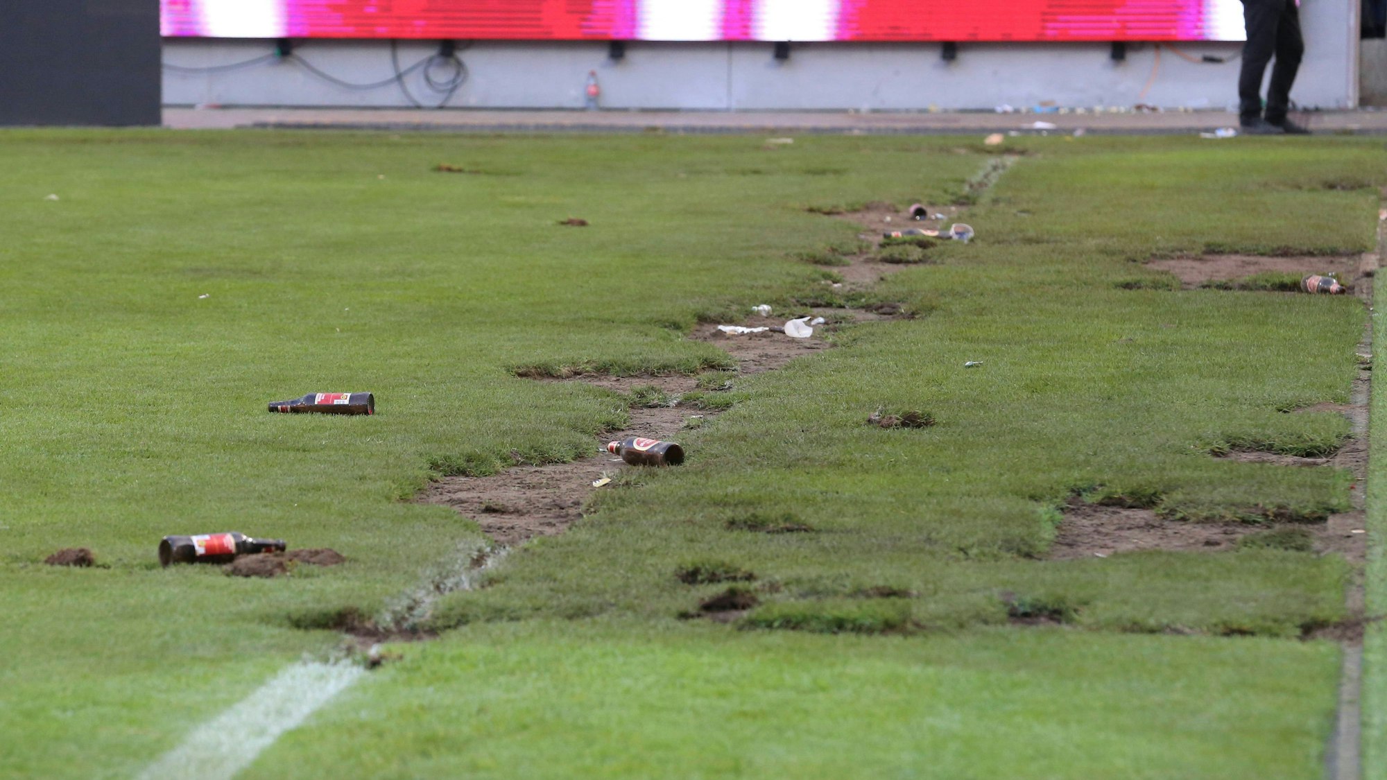 Bierflaschen und Löcher: Der Rasen im Rhein-Energie-Stadion ist nach dem Platzsturm am Sonntag in großen Teilen zerstört.