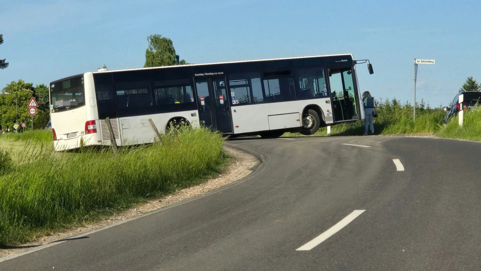 In einer Kurve steht ein Bus und versperrt die ganze Straße. Das rechte Vorderrad ist vom Boden abgehoben.