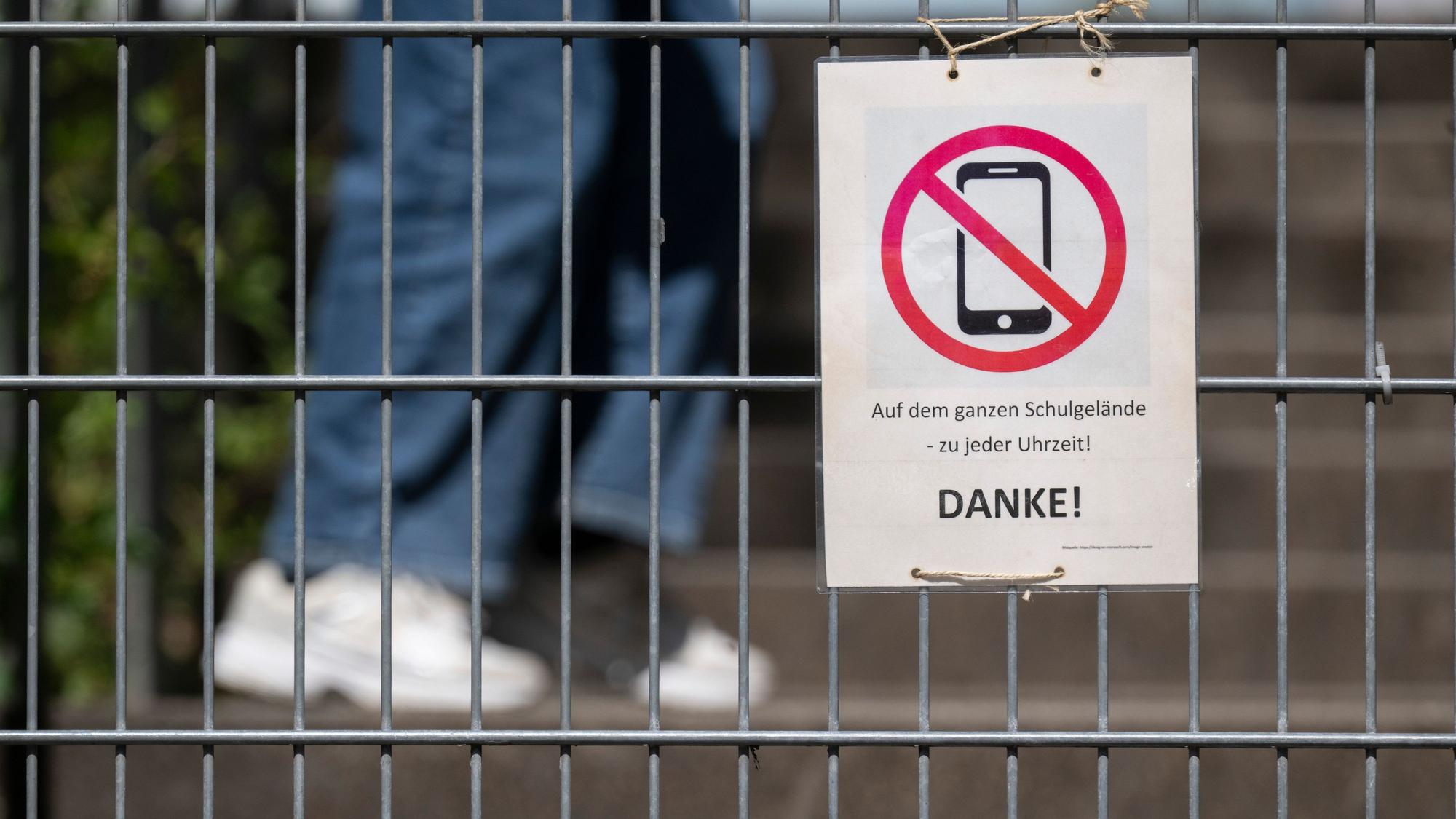 Ein Schild mit einem durchgestrichenen Smartphone und der Aufschrift «Auf dem ganzen Schulgelände - zu jeder Uhrzeit! DANKE!»