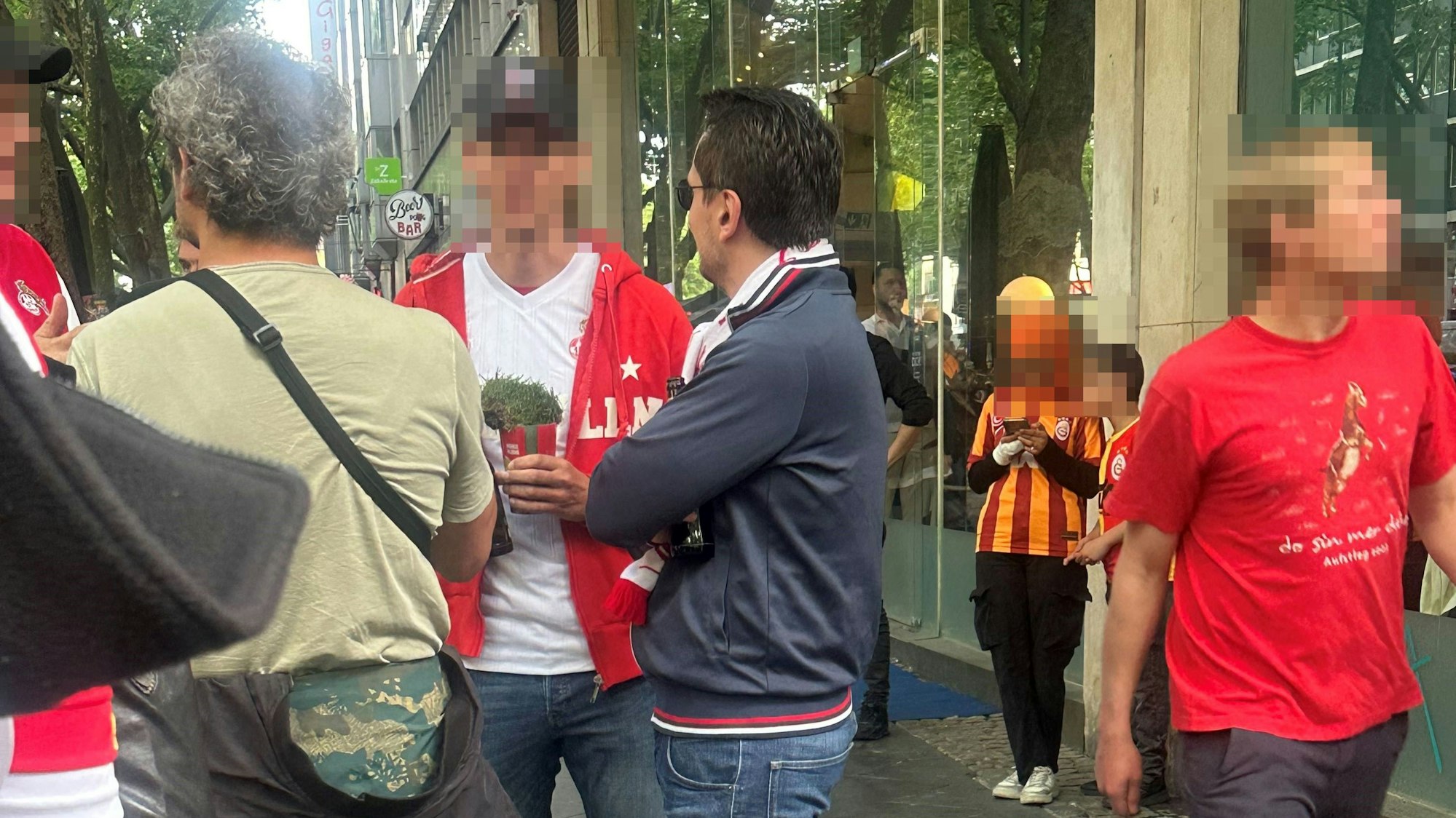 Ein FC-Fan trägt ein Rasenstück, mutmaßlich aus dem Rhein-Energie-Stadion, in einem Getränkebecher mit sich herum.