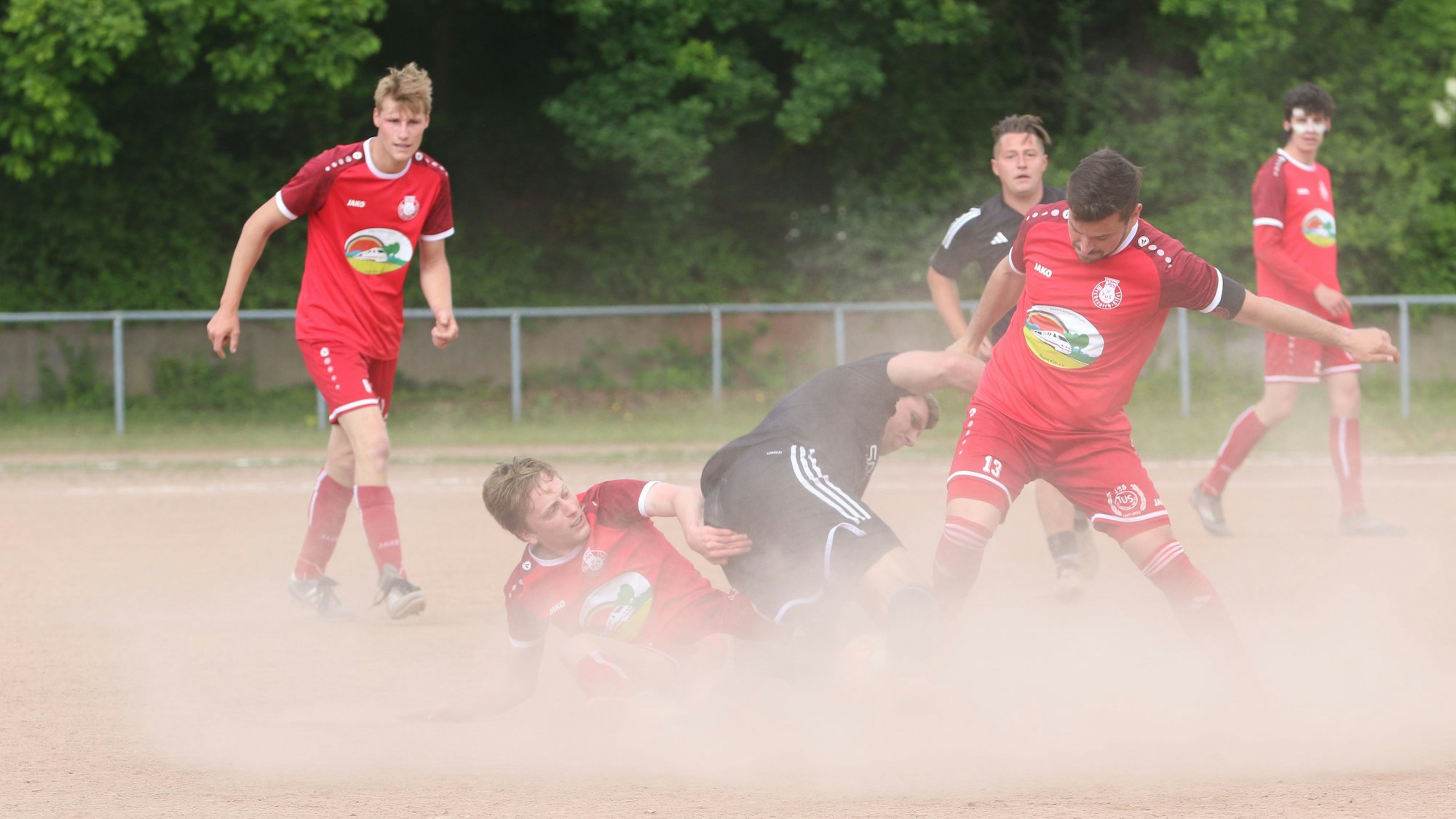 Der Ball ist nicht mehr zu sehen. Drei Spieler von Mechernich und Frauenberg kämpfen um den Ball und es staubt gewaltig.
