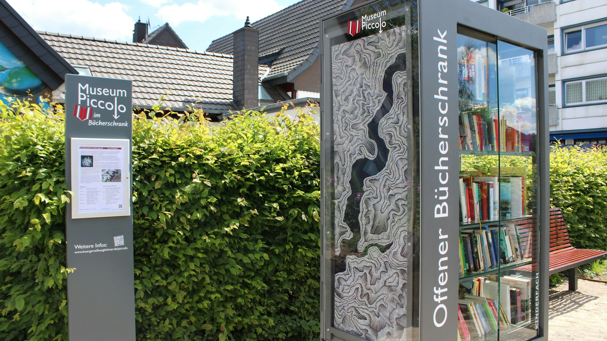 Die Stele neben dem Bücherschrank bietet Platz für Informationen zur Künstlerin und ihrer Technik.