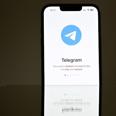 Ein Handydisplay ist zu sehen mit Telegram-Logo.