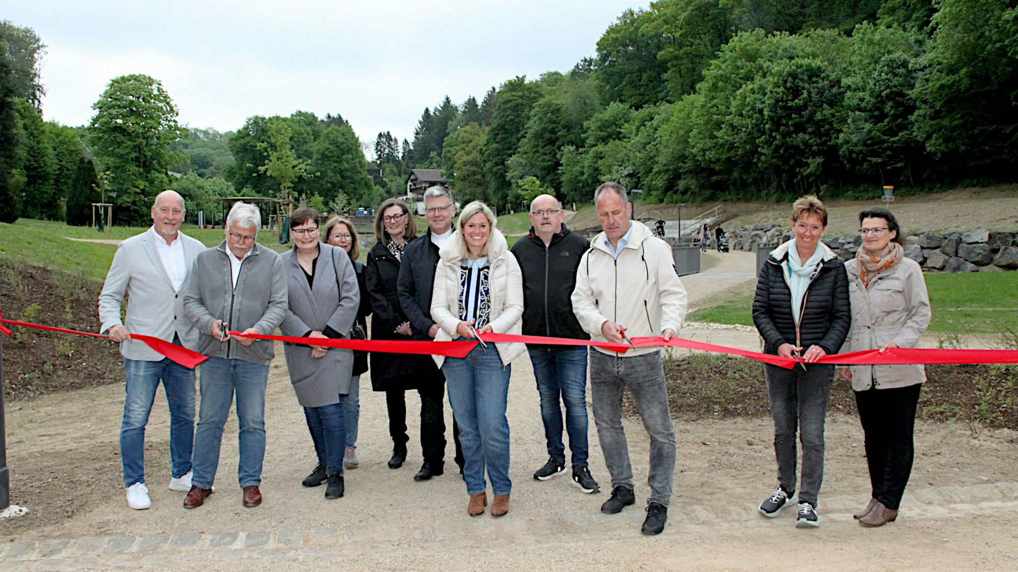 Eine Gruppe Menschen steht hinter einem roten Band und schneidet dieses durch.