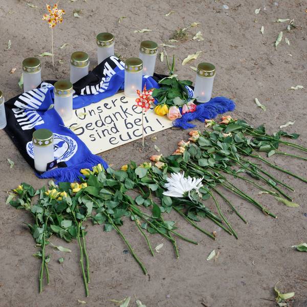 Bielefeld: Kerzen und ein Fanschal von Arminia Bielefeld sind an einem Tatort in der Innenstadt zu sehen. Nach dem Angriff eines Mannes auf mindestens fünf Menschen vor einer Bar in Bielefeld ist ein Tatverdächtiger festgenommen worden.