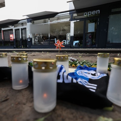 20.05.2025, Nordrhein-Westfalen, Bielefeld: Kerzen und ein Fanschal von Arminia Bielefeld sind an einem Tatort in der Innenstadt zu sehen. Nach dem Angriff eines Mannes auf mindestens fünf Menschen vor einer Bar in Bielefeld ist ein Tatverdächtiger in Untersuchungshaft. Betroffene des Messerangriffs vor einer Bielefelder Bar können bei einer kostenlosen Hotline Hilfe und psychosoziale Beratung bekommen. Wie der Bundesopferbeauftragte Roland Weber mitteilte, sei eine entsprechend kostenfreie Telefonnummer nun freigeschaltet worden. (zu dpa: «Beratungstelefon für Betroffene des Angriffs von Bielefeld») Foto: Friso Gentsch/dpa +++ dpa-Bildfunk +++